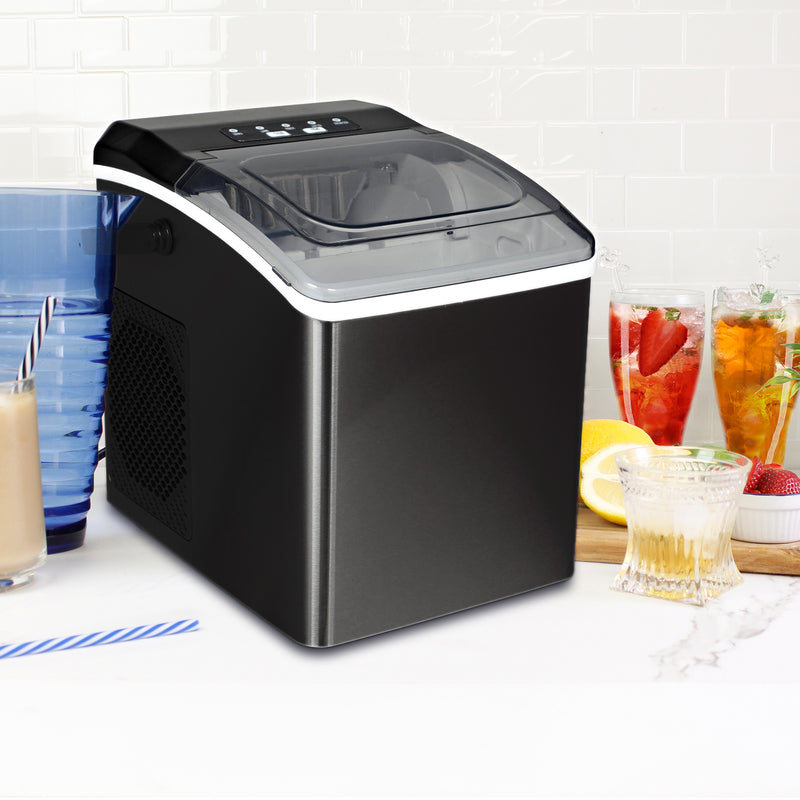 Stainless steel ice maker on a white countertop with white tile backsplash behind and glasses of juice, iced tea, water, and iced coffee on either side