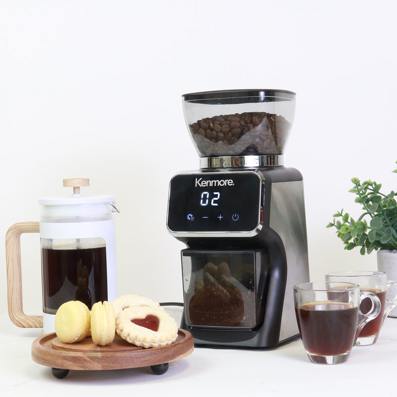 Kenmore digital burr coffee grinder conical burr grinder with a white French Press coffeemaker, a tray of cookies, and two cups of coffee arranged around it