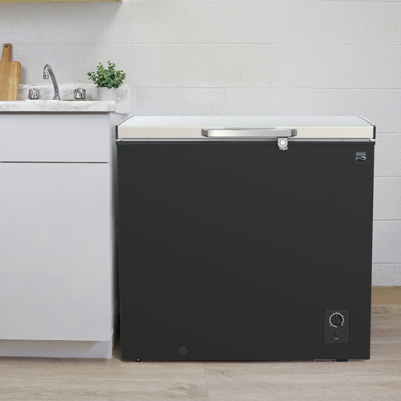 Kenmore chest freezer, closed, with white kitchen cabinets and a stainless steel sink to the left