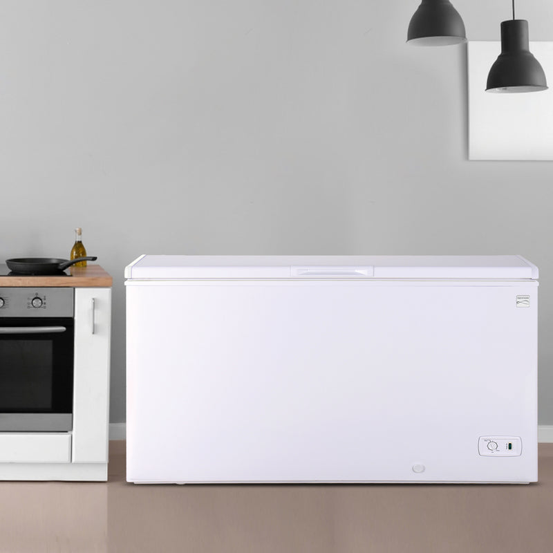 Kenmore chest freezer, closed, in a light gray kitchen with black pendulum lights above and white cabinet with a black and stainless steel stove to the left