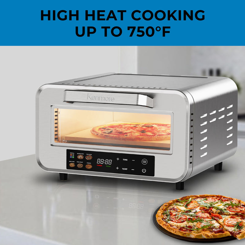 Kenmore portable countertop pizza oven with a pizza cooking inside and another beside it on a light gray counter. Text above reads, "High heat cooking up to 750°F"