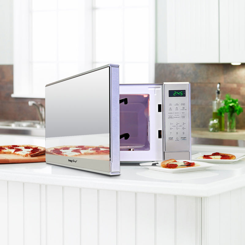 Total Chef 0.7 cu ft stainless steel microwave, partly open, with slices of pizza on plates arranged around it on a white counter in a modern-looking kitchen